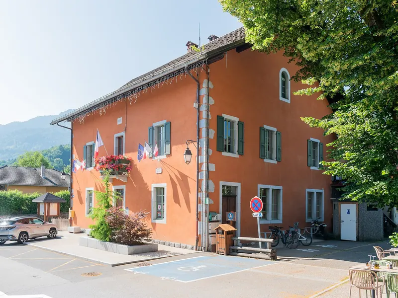 La mairie de Morillon, façade orangée et place fleurie
